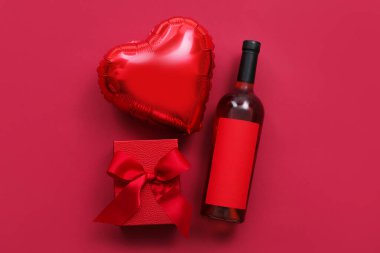 Bottle of wine, balloon and gift box on color background. Valentine's Day celebration