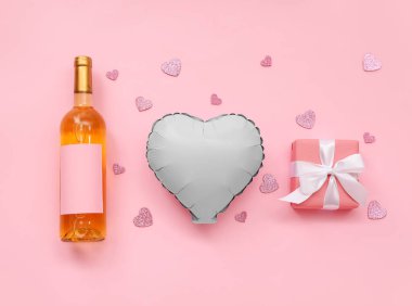 Composition with bottle of wine, balloon and gift box on pink background. Valentine's Day celebration