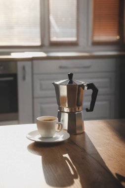 Geyser coffee maker and cup on table in kitchen