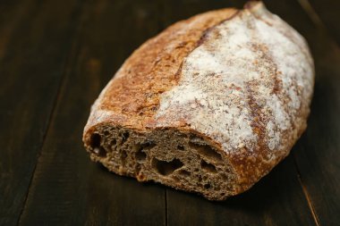 Loaf of fresh rye bread on black table