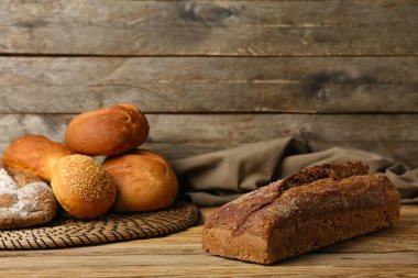 Loaves of different bread on wooden table