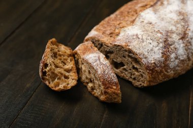 Sliced loaf of fresh rye bread on black table