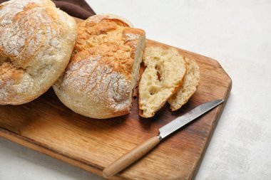 Cutting board with sliced loaf of fresh bread on white table