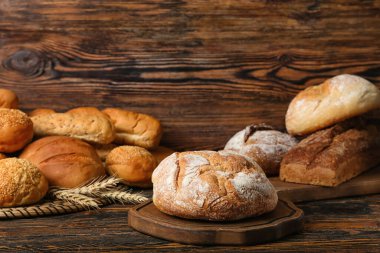 Loaves of different bread on wooden table