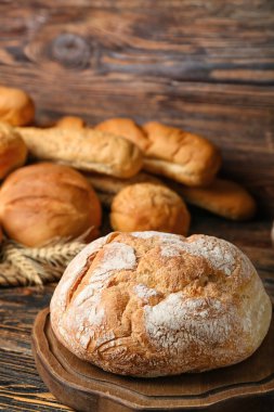 Cutting board with loaf of fresh bread on wooden table