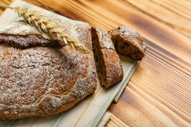 Sliced loaf of rye bread and wheat ear on wooden background
