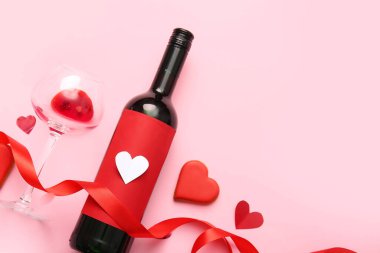 Composition with bottle of wine, glass, cookie and ribbon on pink background. Valentines Day celebration