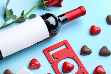Bottle of wine and chocolate candies on blue background. Valentine's Day celebration