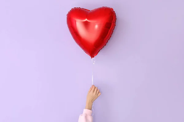 Woman with heart shaped balloon for Valentine\'s Day on lilac background