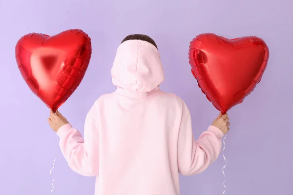 Woman with heart shaped balloons for Valentine\'s Day on lilac background, back view