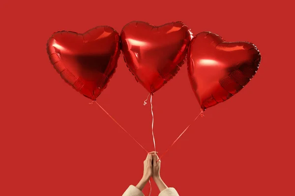 Woman with heart shaped balloons for Valentine\'s Day on red background