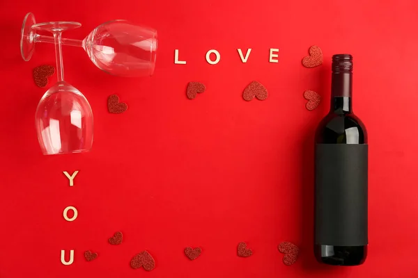 Frame made of bottle of wine, words LOVE YOU, glasses and hearts on red background. Valentine\'s Day Celebration