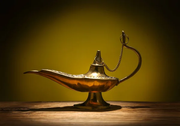 Aladdin lamp of wishes for Ramadan on table against dark yellow background