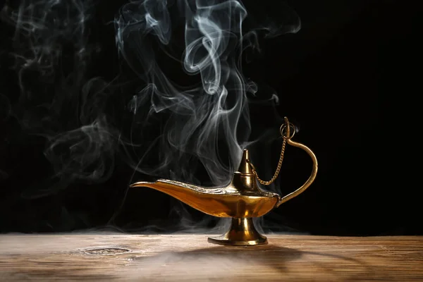 Aladdin lamp of wishes with smoke for Ramadan on table against dark background