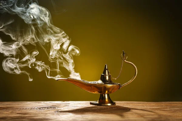 Aladdin lamp of wishes with smoke for Ramadan on table against dark yellow background