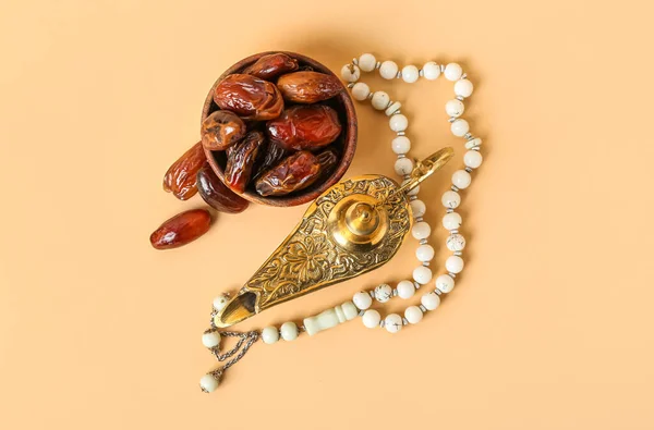 Aladdin lamp of wishes, dates and prayer beads for Ramadan on beige background