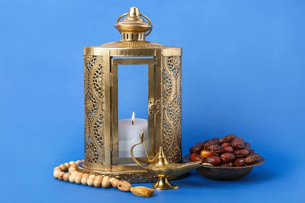 Aladdin lamp of wishes, dates, prayer beads and Muslim lantern for Ramadan on blue background