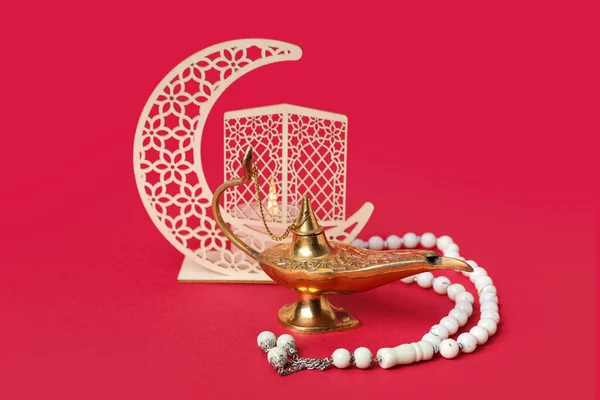 Aladdin lamp of wishes, prayer beads and decorative crescent for Ramadan on red background
