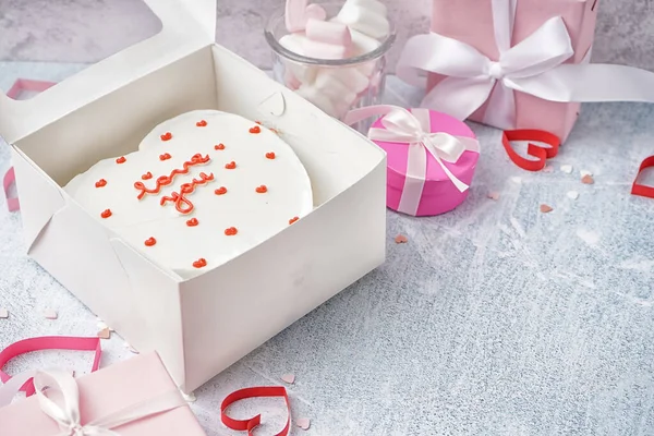 Box with tasty bento cake, gifts and hearts on grey table. Valentine\'s Day celebration