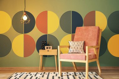 Stylish armchair and table near wall with abstract picture
