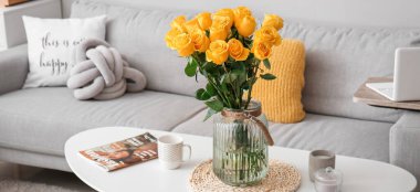 Yellow roses in vase on table in living room