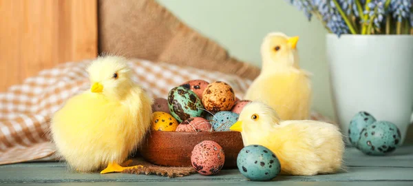Cute chickens, Easter eggs and flowers on table