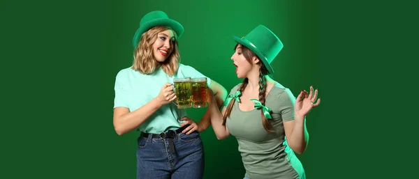 Funny young women with beer on green background. St. Patrick\'s Day celebration