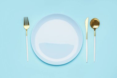 Table setting with golden cutlery on blue background