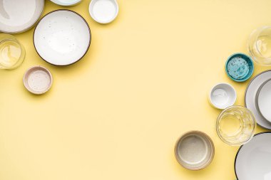 Different clean dishware on yellow background