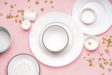 Different clean dishware with floral decor on pink background