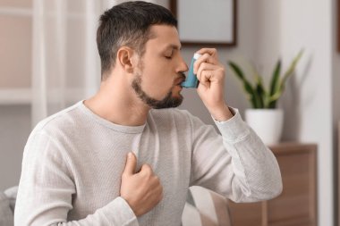 Sick man using inhaler at home