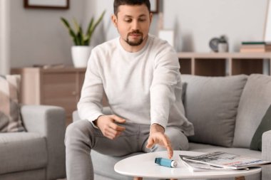 Man taking inhaler from table