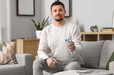 Portrait of man with inhaler at home