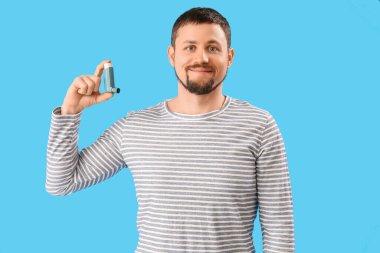 Man with inhaler on blue background