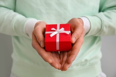 Man with gift box for Valentine's Day on grey background, closeup