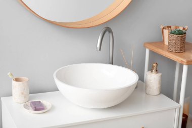 Ceramic sink and bath accessories on drawers in bathroom