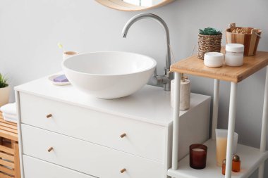 Ceramic sink and bath accessories on drawers in bathroom
