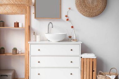 Interior of bathroom with ceramic sink, drawers and shelving unit