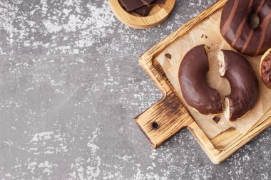 Board with delicious chocolate donuts on grey table