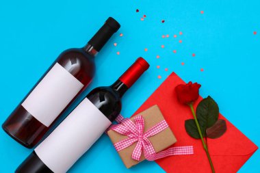 Composition with bottles of wine, gift box, envelope and rose flower on color background. Valentines Day celebration