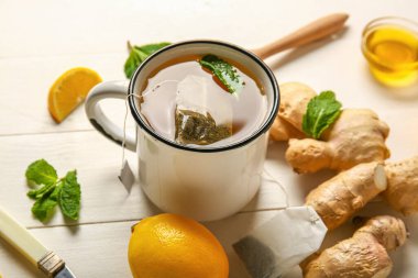 Cup of tea with mint, ginger and lemon on wooden background