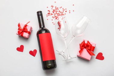 Composition with bottle of wine, gifts and glasses on light background. Valentines Day celebration