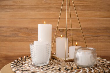 Wicker mat with burning candles near wooden wall