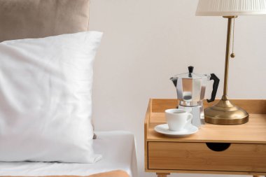 Geyser coffee maker and cup of espresso on nightstand near bed