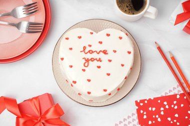 Plate with heart-shaped bento cake and cup of coffee on white background. Valentine's Day celebration