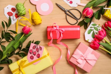 Composition with gift boxes, tulip flowers and packing materials on wooden background.  International Women's Day celebration