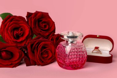 Perfume with engagement ring and roses for Valentine's day on pink background