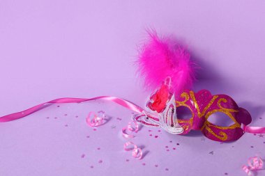 Carnival mask for Mardi Gras celebration with confetti and serpentine on lilac background