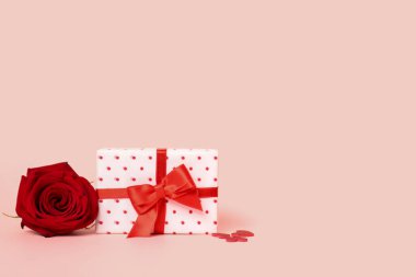Gift box with beautiful bow and rose flower on pink background. Valentine's Day celebration