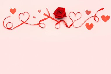 Rose flower and heart made of red satin ribbon on pink background. Valentine's Day celebration